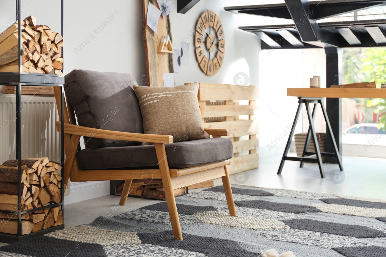 Photo of Firewood near armchair in stylish room interior