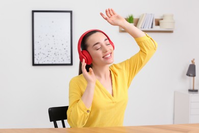 Happy woman in headphones listening music and dancing at home
