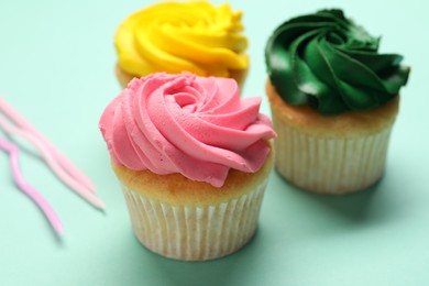 Delicious cupcakes with bright cream on turquoise background, closeup