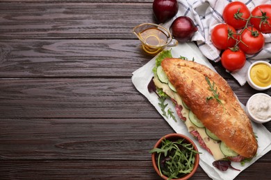 Photo of Delicious sandwich with tasty filling and ingredients on wooden table, flat lay. Space for text