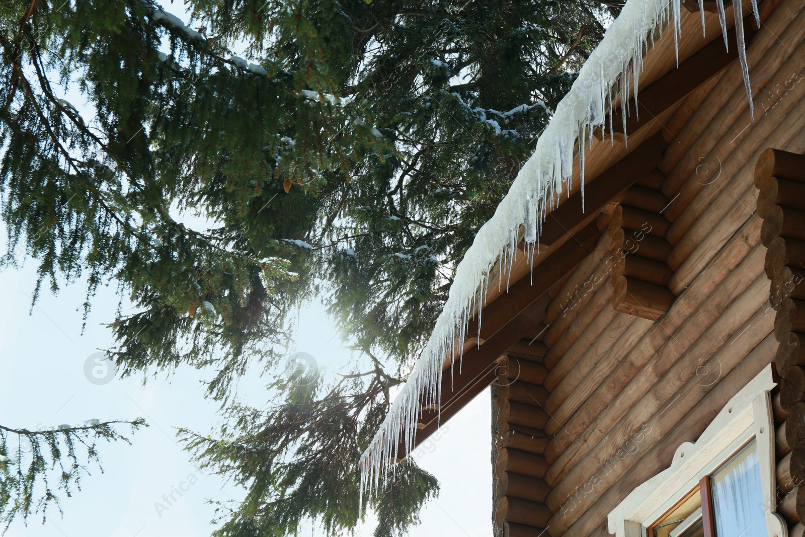 Photo of House with icicles on roof, low angle view. Winter season