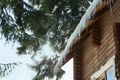 House with icicles on roof, low angle view. Winter season