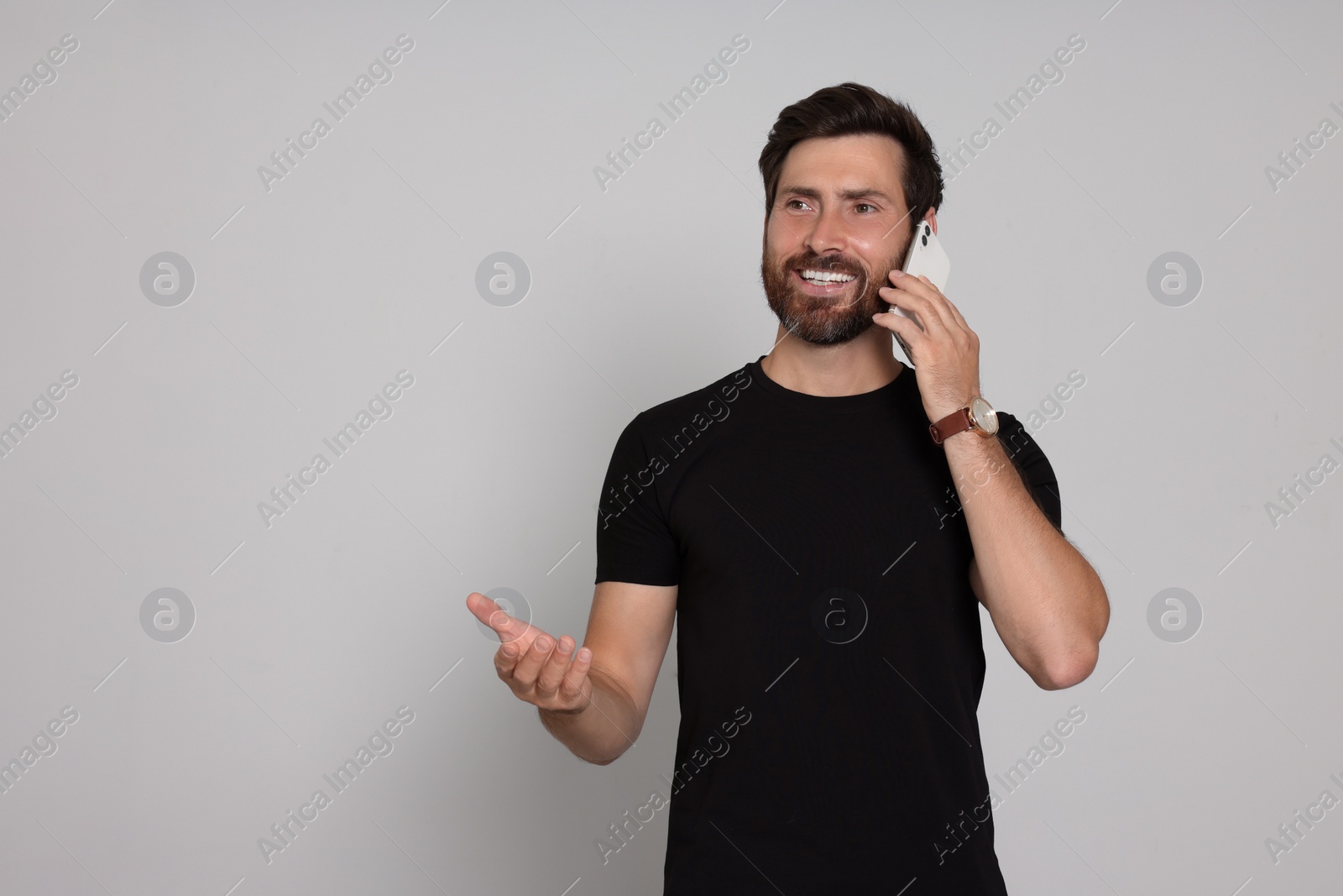 Photo of Happy man talking on phone against light background. Space for text