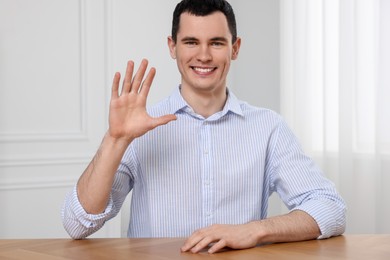 Man waving hello while having video chat indoors, view from web camera