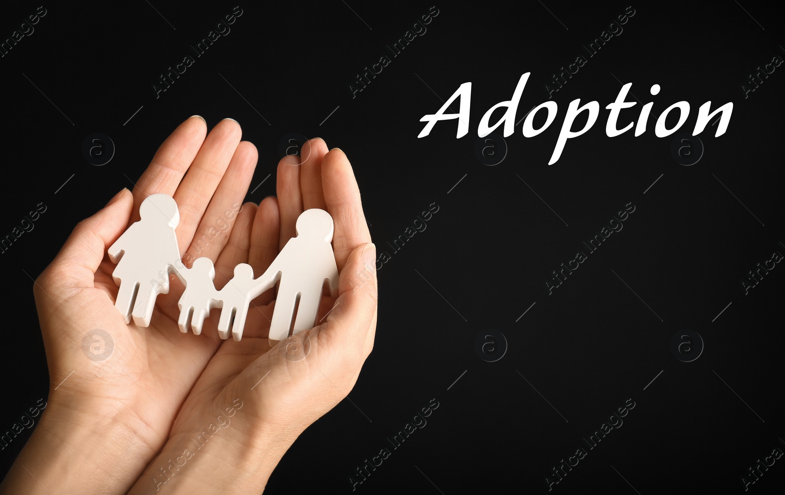 Image of Woman holding figure of family in hands on black background, closeup. Child adoption concept