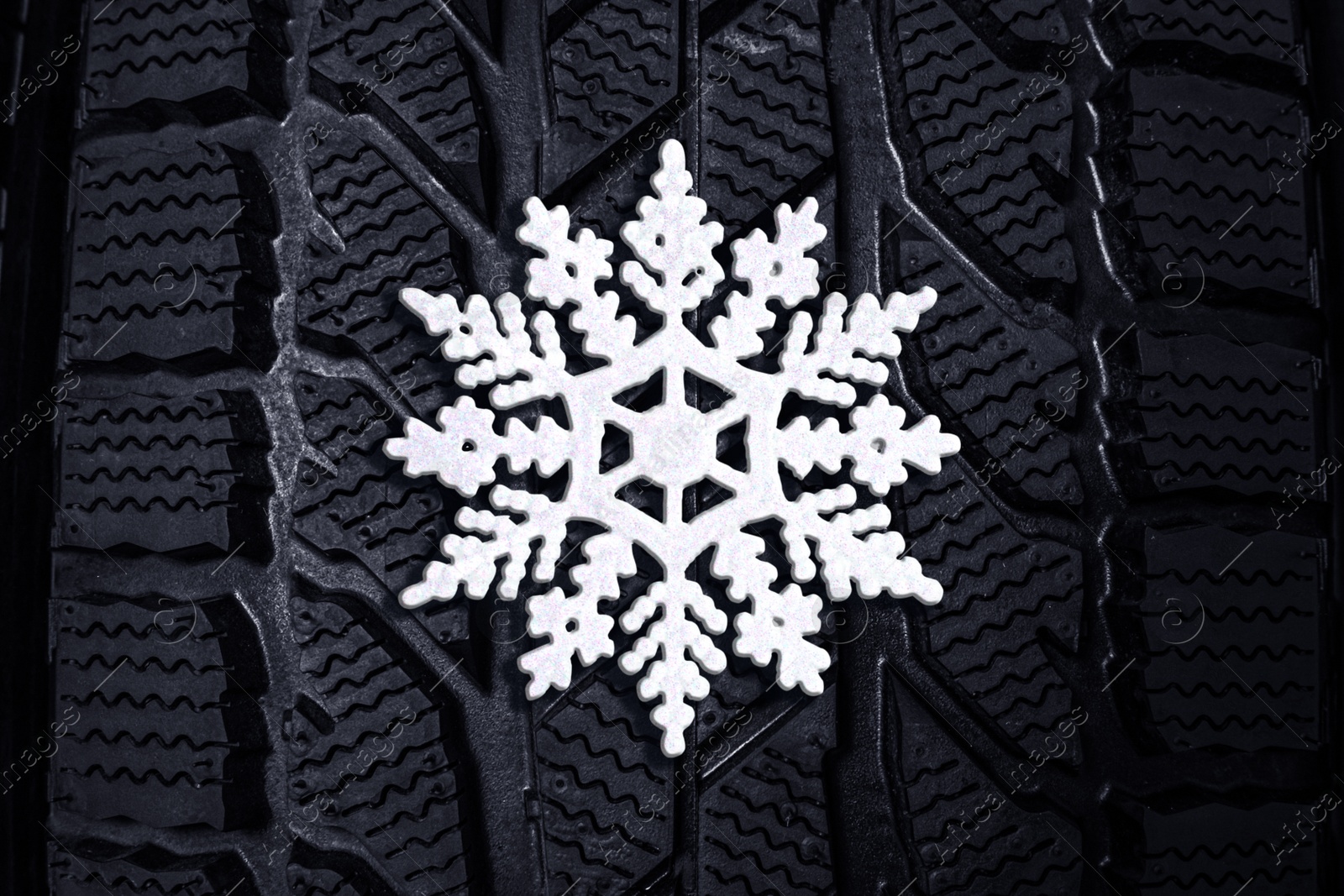 Image of Winter tire with snowflake as background, closeup