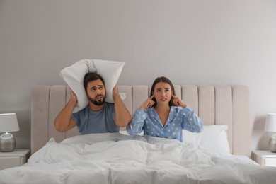 Young couple suffering from noisy neighbours in bed at home