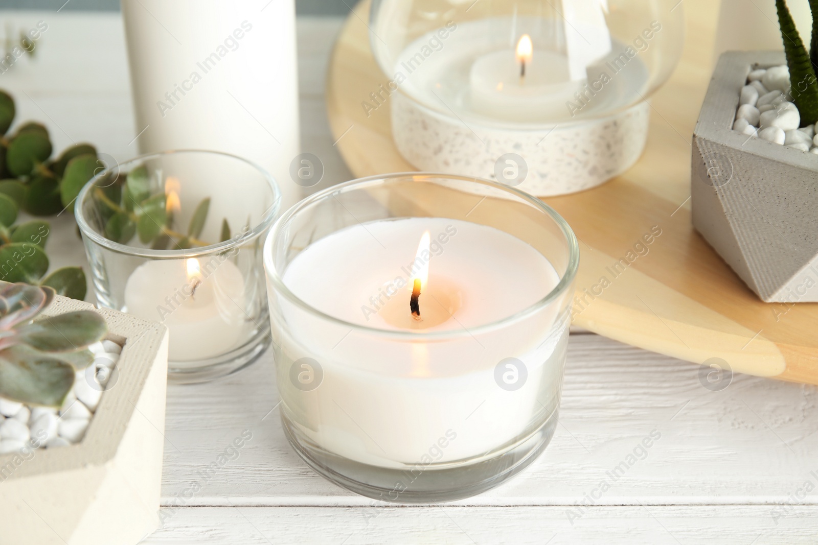 Photo of Burning aromatic candle and plants on table