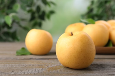 Photo of Ripe apple pears on wooden table against blurred background. Space for text