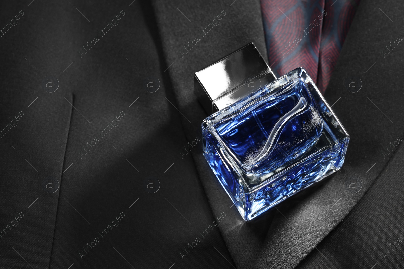 Photo of Luxury men's perfume in bottle on black jacket, space for text