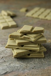 Photo of Stacked pieces of tasty matcha chocolate on textured table, closeup