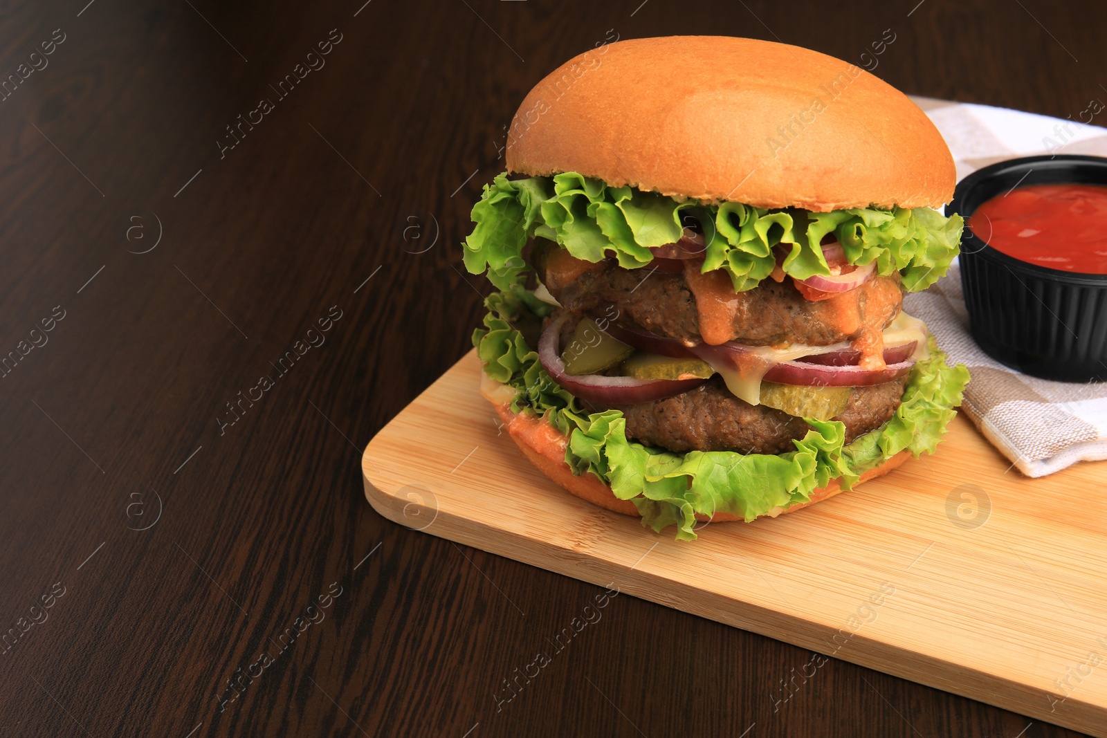 Photo of Board of tasty burger served with ketchup on wooden table. Space for text