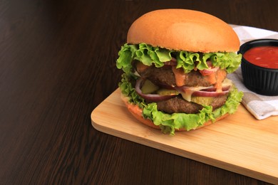 Board of tasty burger served with ketchup on wooden table. Space for text