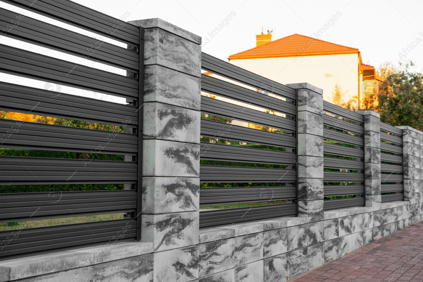 Photo of Beautiful stone fence with iron railing near pathway outdoors