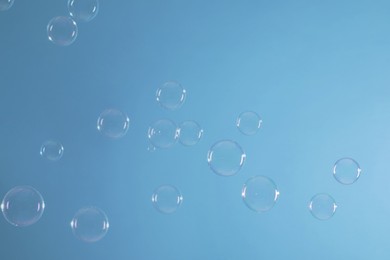 Photo of Many beautiful soap bubbles on light blue background