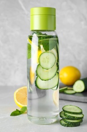 Bottle of refreshing water with cucumber, lemon and mint on light grey table