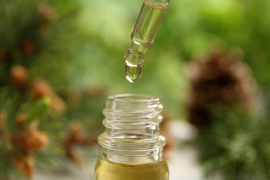 Photo of Pipette and bottle of essential oil on blurred background, closeup