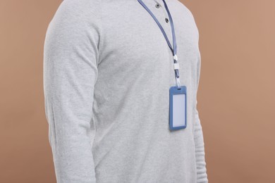 Man with blank badge on beige background, closeup