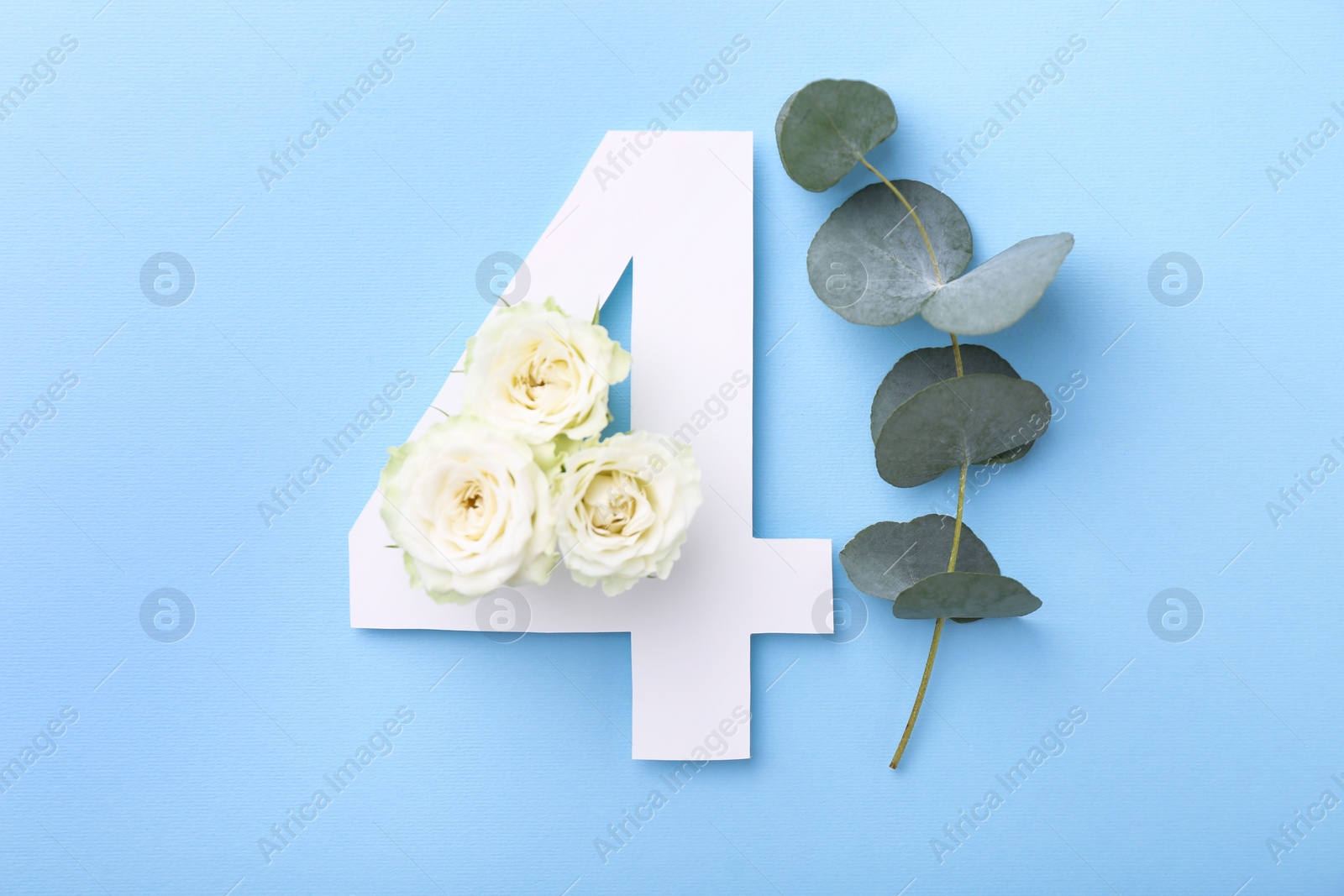 Photo of Paper number 4, beautiful flowers and eucalyptus branch on light blue background, top view