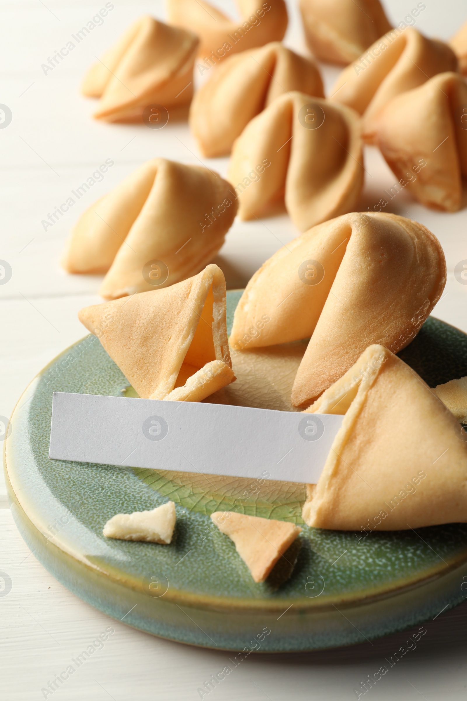 Photo of Tasty fortune cookies and paper with prediction on white wooden table, space for text