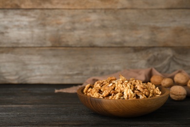 Dish with walnuts on wooden table. Space for text