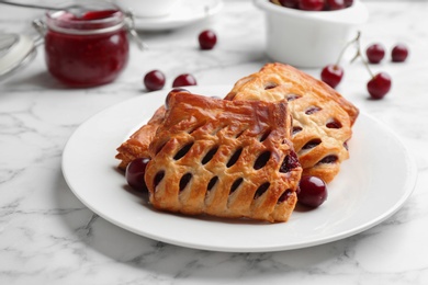 Photo of Fresh delicious puff pastry with sweet cherries served on white marble table