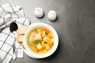 Homemade chicken soup served on grey table, top view with space for text