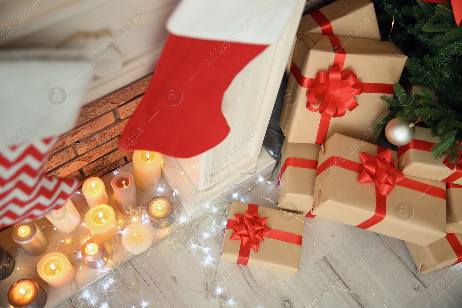 Photo of Decorative fireplace with stockings near beautiful Christmas tree and gifts indoors