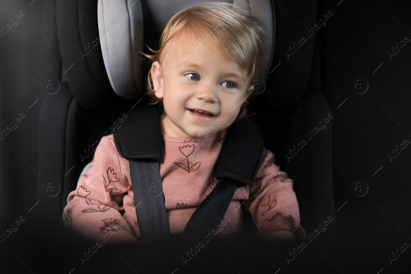 Photo of Cute little girl sitting in child safety seat inside car