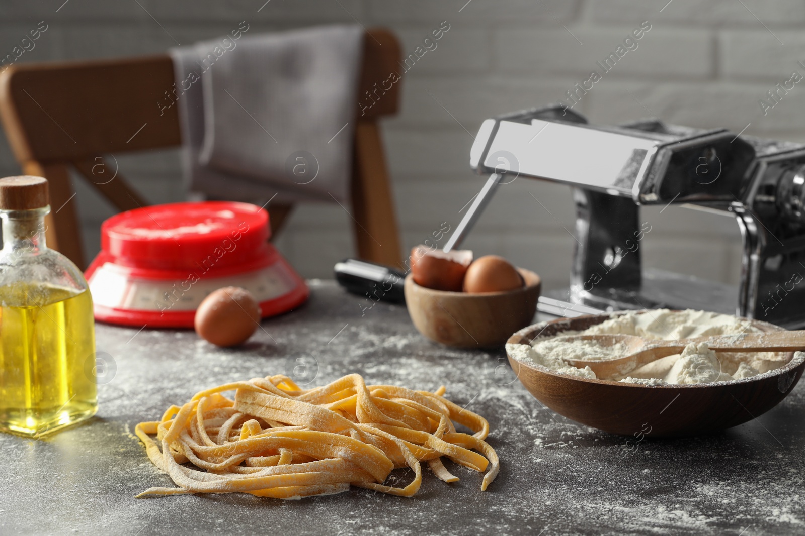 Photo of Homemade pasta, maker and ingredients on dark grey table