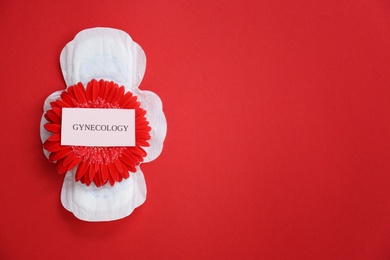 Photo of Flat lay composition with red flower and menstrual pad on color background. Gynecological care