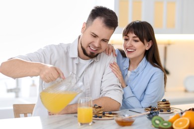 Happy couple having tasty breakfast at home