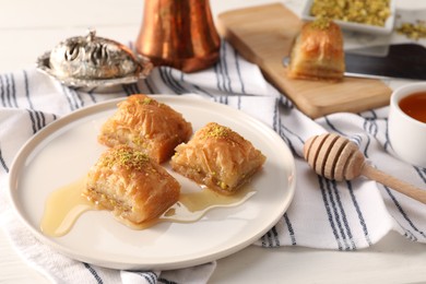 Delicious sweet baklava with pistachios and honey on table