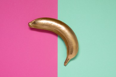 Golden banana on color background, top view