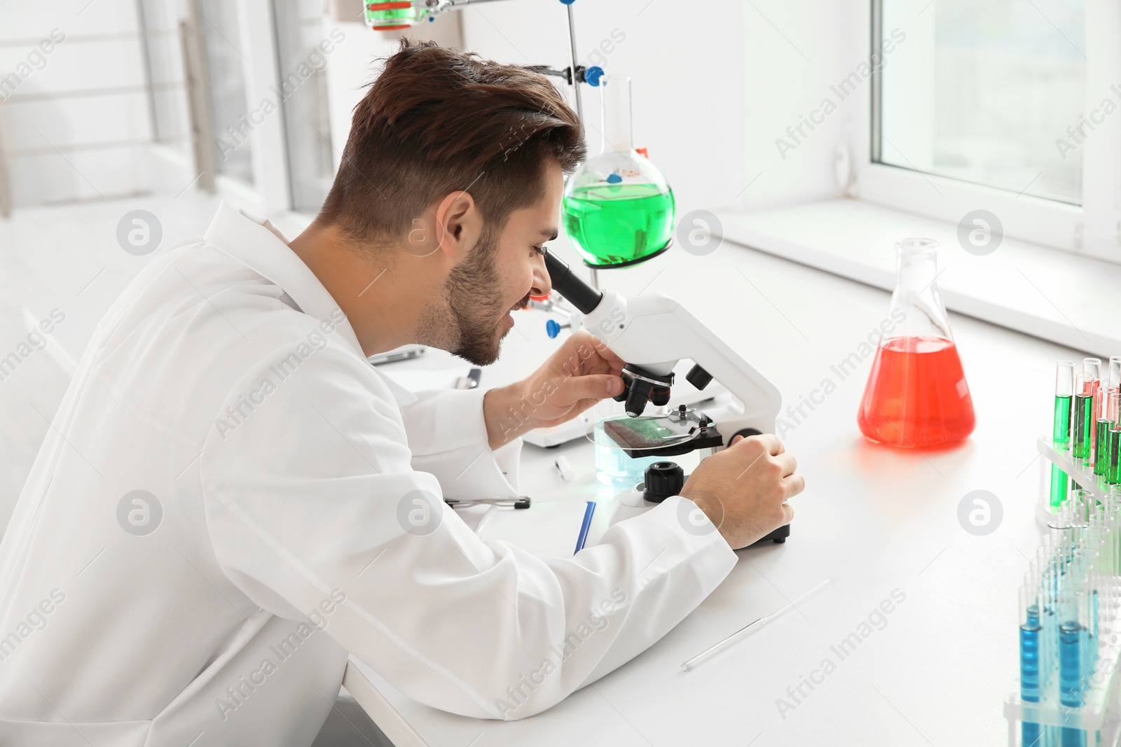 Photo of Medical student working with microscope in modern scientific laboratory