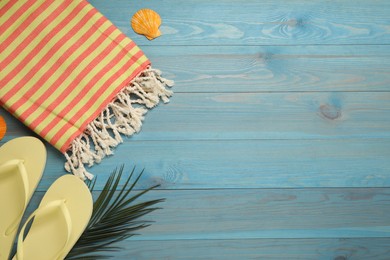 Photo of Beach towel and flip flops on light blue wooden background, flat lay. Space for text