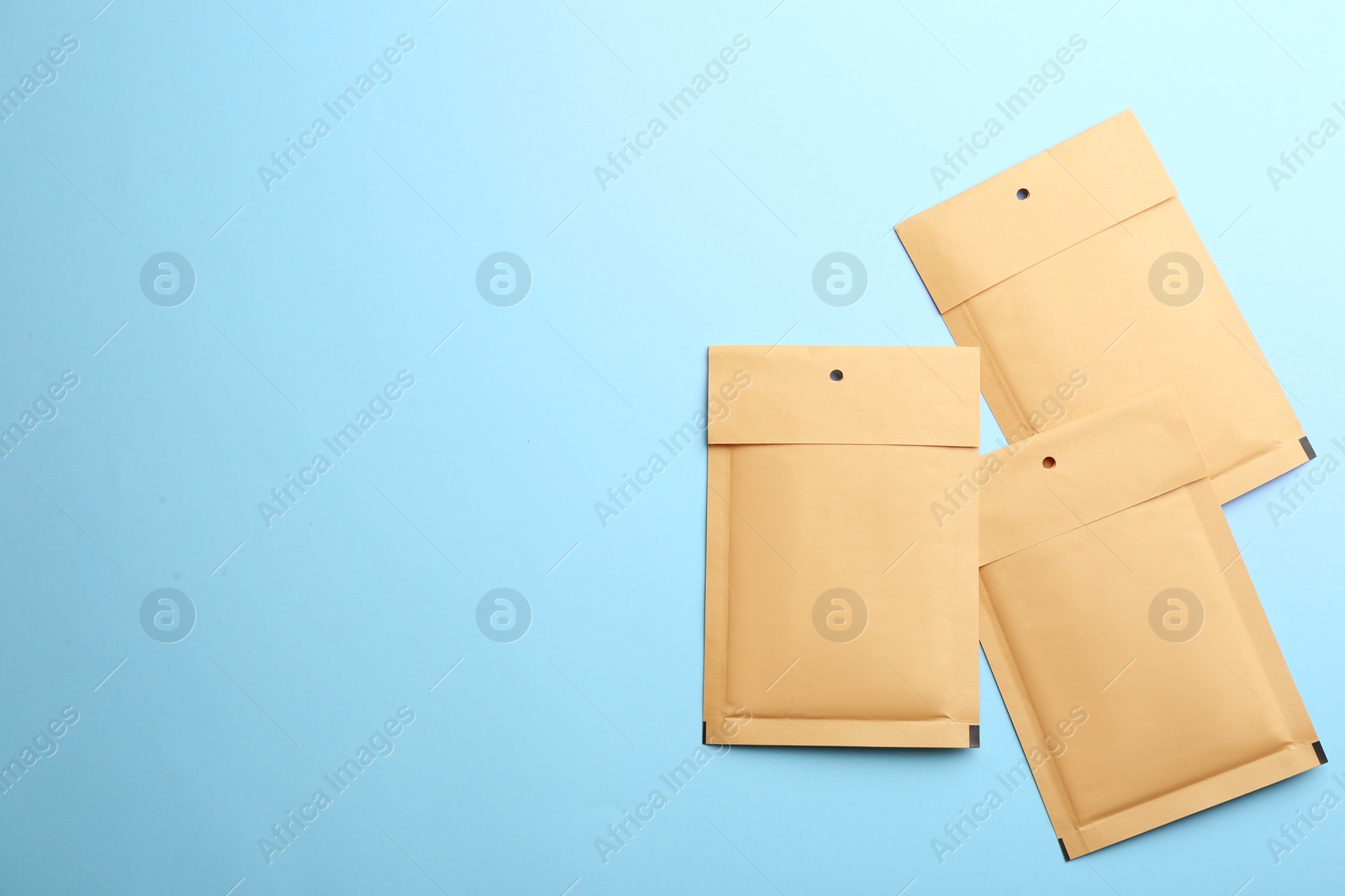 Photo of Kraft paper envelopes on light blue background, flat lay. Space for text