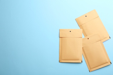Kraft paper envelopes on light blue background, flat lay. Space for text