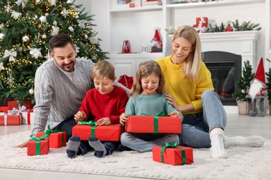 Photo of Parents and their children opening Christmas gifts at home