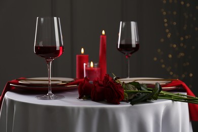 Place setting with roses and candles on white table. Romantic dinner