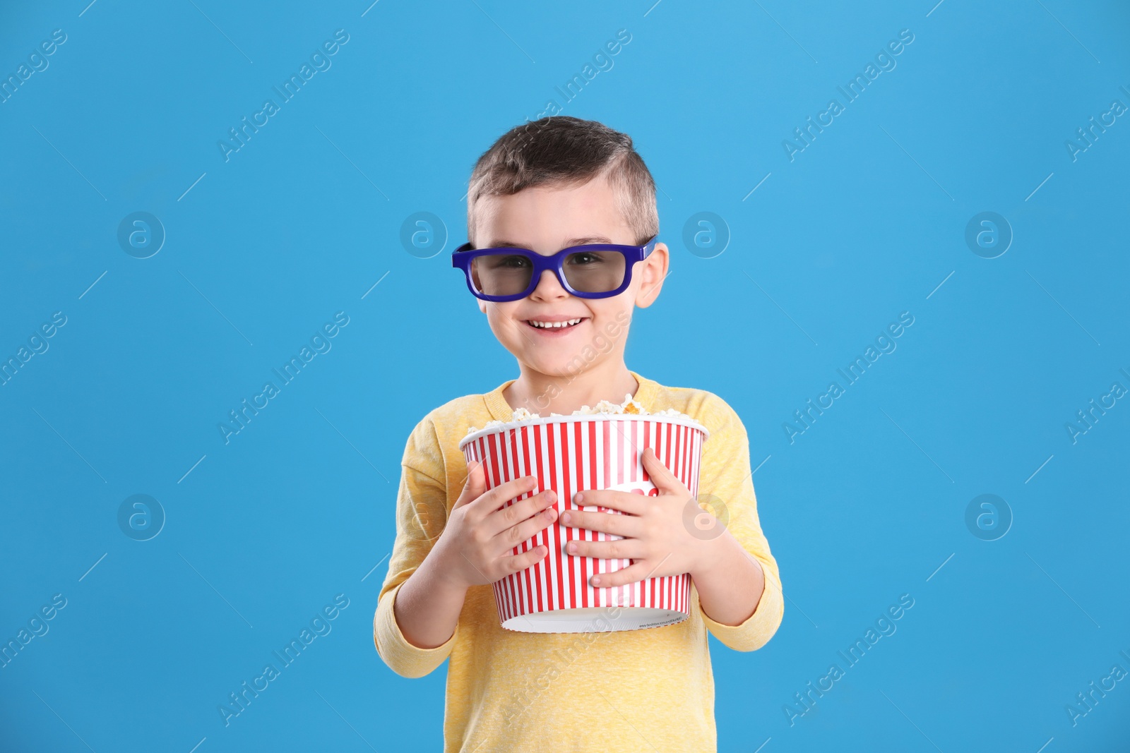 Photo of Cute little boy with popcorn and glasses on color background