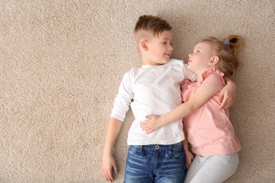 Photo of Cute little children lying on cozy carpet at home, top view