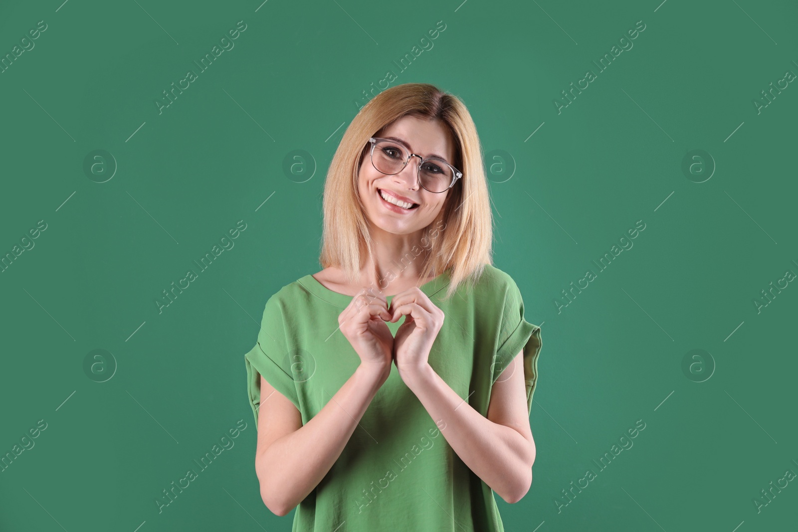 Photo of Portrait of woman making heart with her hands on color background