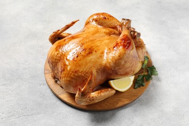Photo of Tasty roasted chicken with parsley and lemon on light grey table