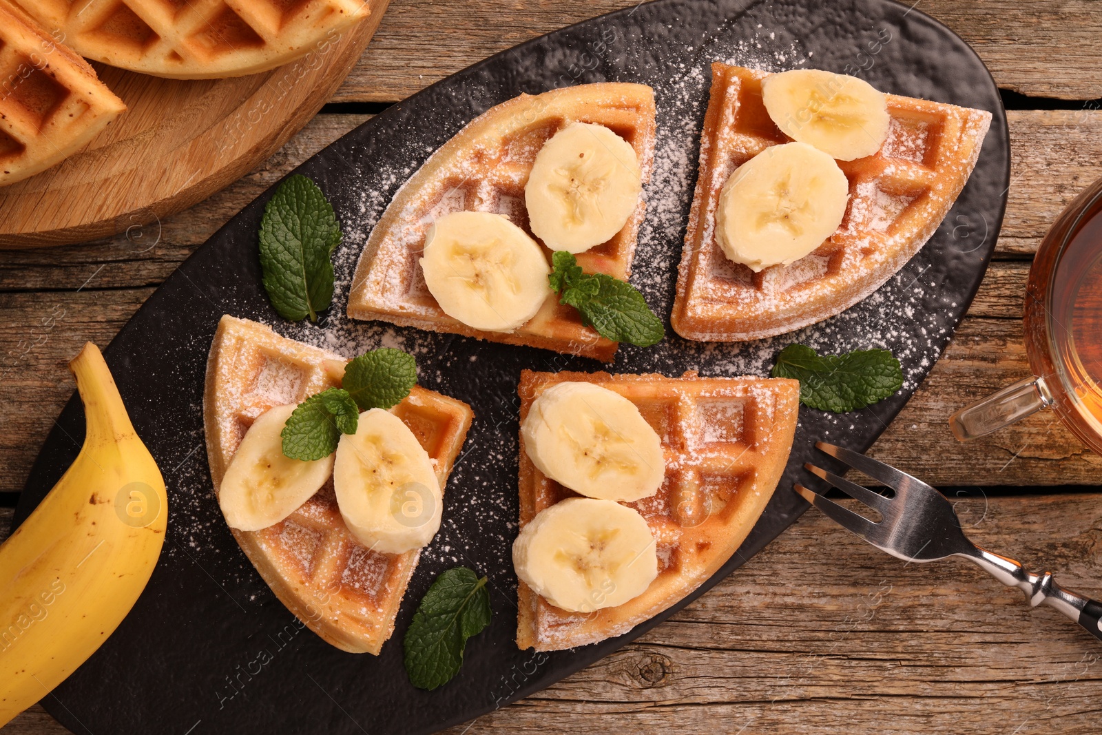 Photo of Tasty Belgian waffles with banana, mint and fork on wooden table, flat lay