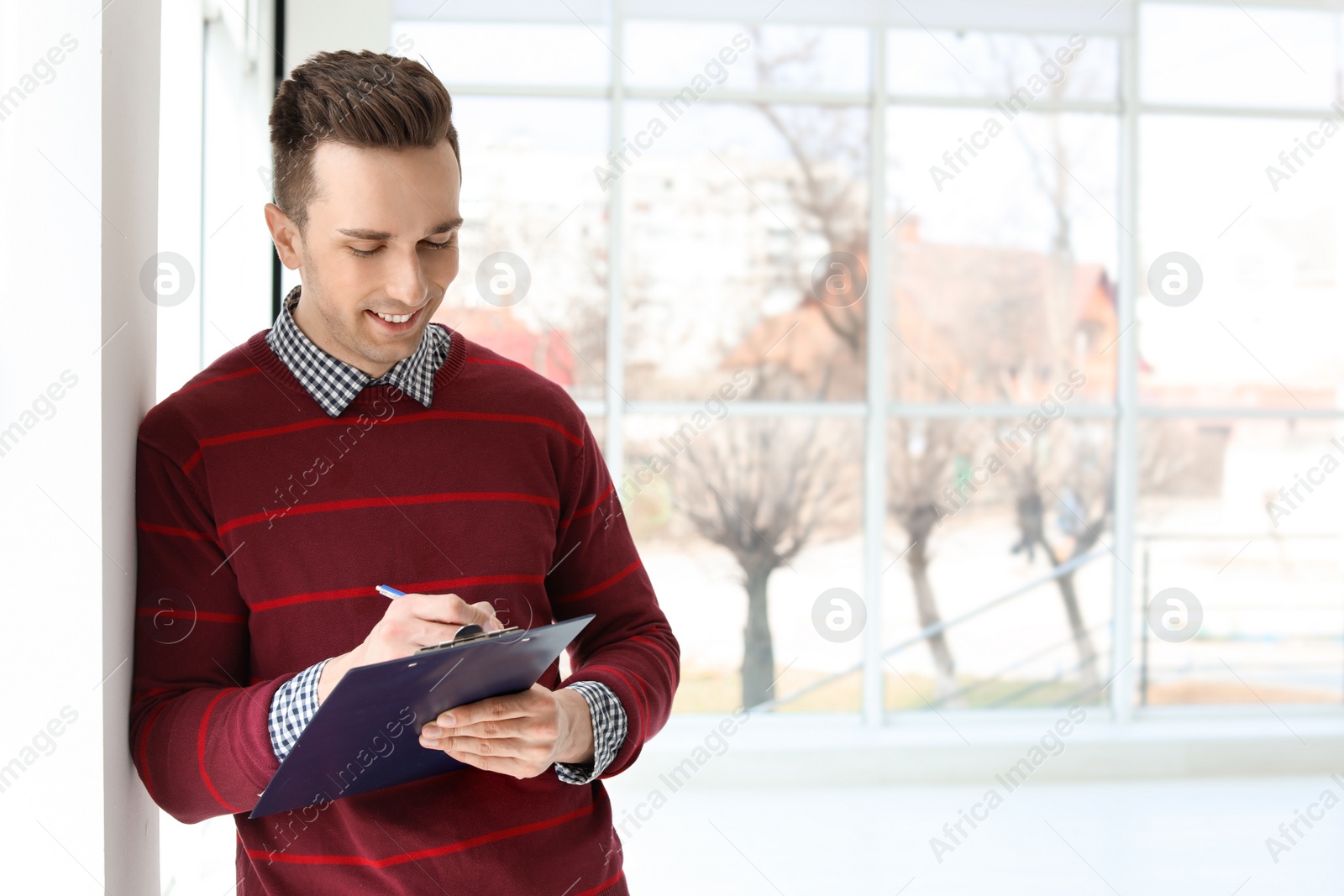 Photo of Male real estate agent with clipboard indoors