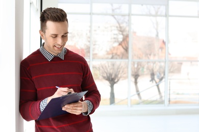 Male real estate agent with clipboard indoors