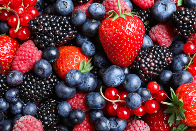 Photo of Mix of different ripe tasty berries as background, top view