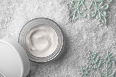 Winter skin care. Stylish presentation of hand cream near decorative snowflakes on artificial snow, flat lay
