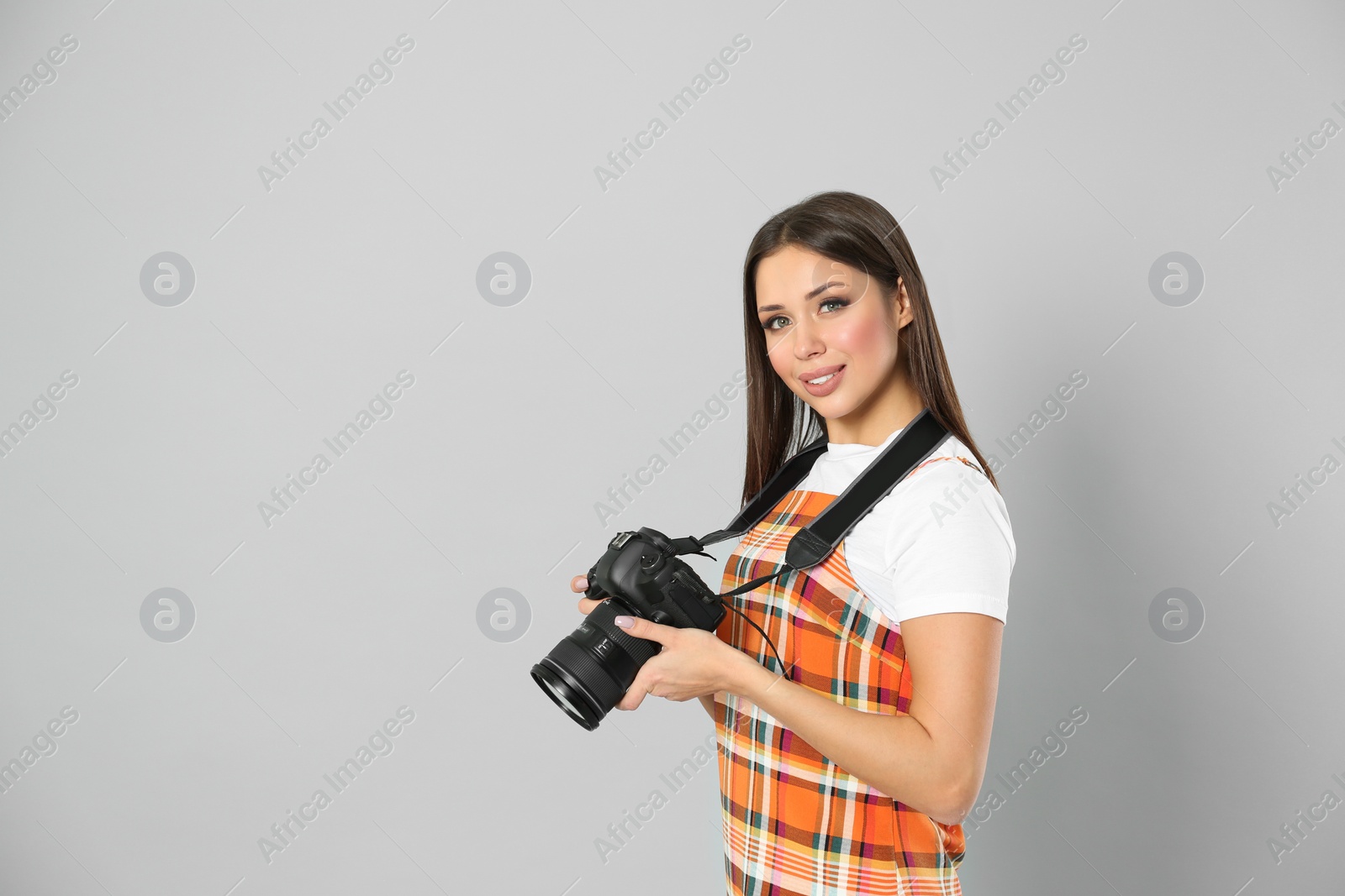 Photo of Professional photographer working on light grey background in studio. Space for text